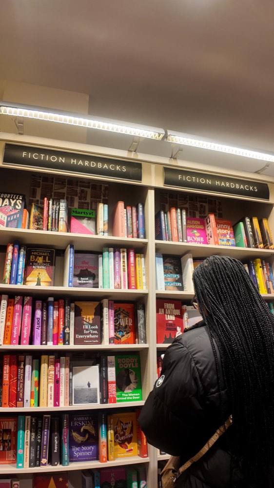 A reader browsing the fiction hardback shelves